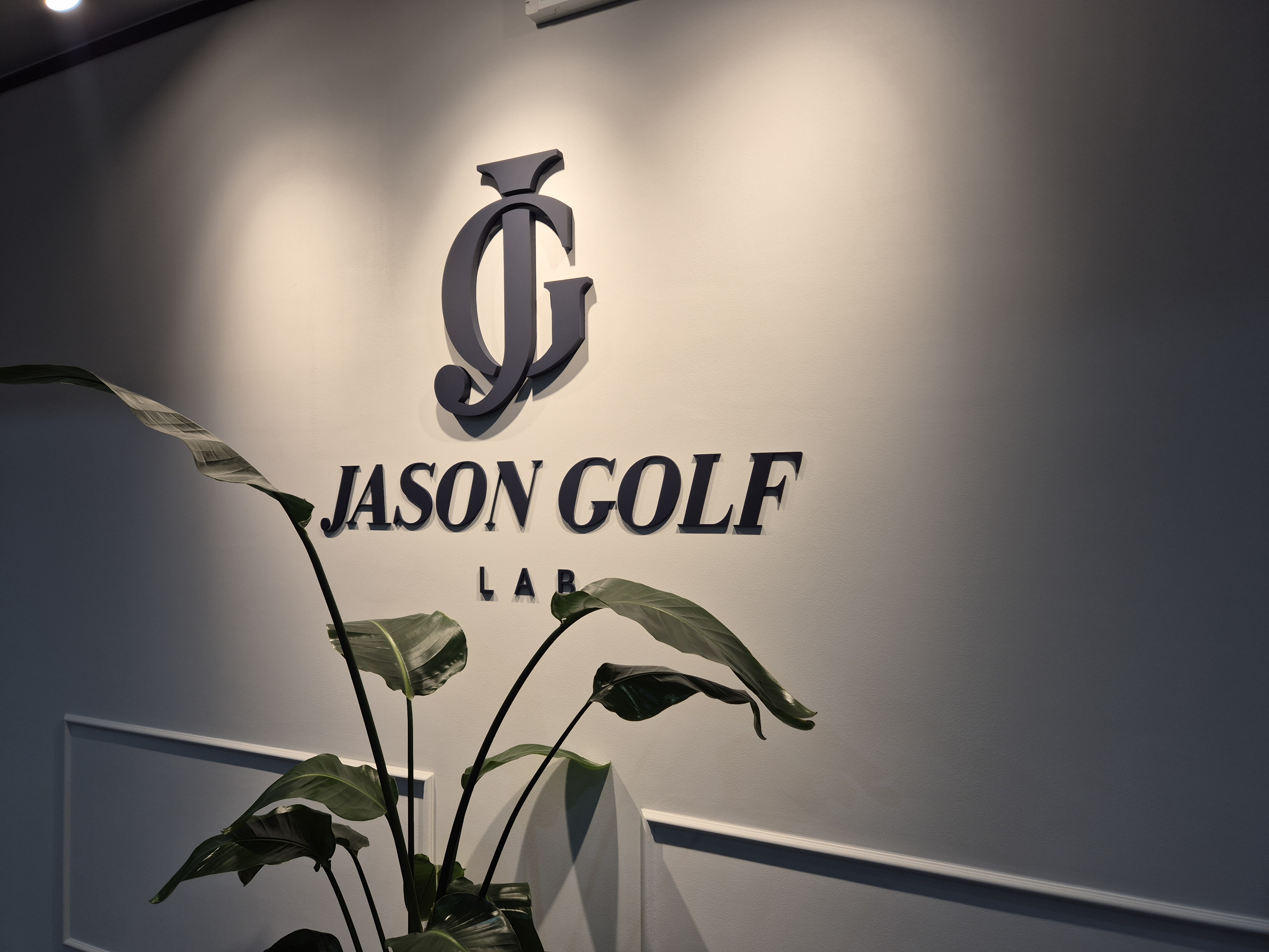 입구 벽면. JASON GOLF LAB 로고가 붙어 있고 앞에 화분이 놓여 있습니다.