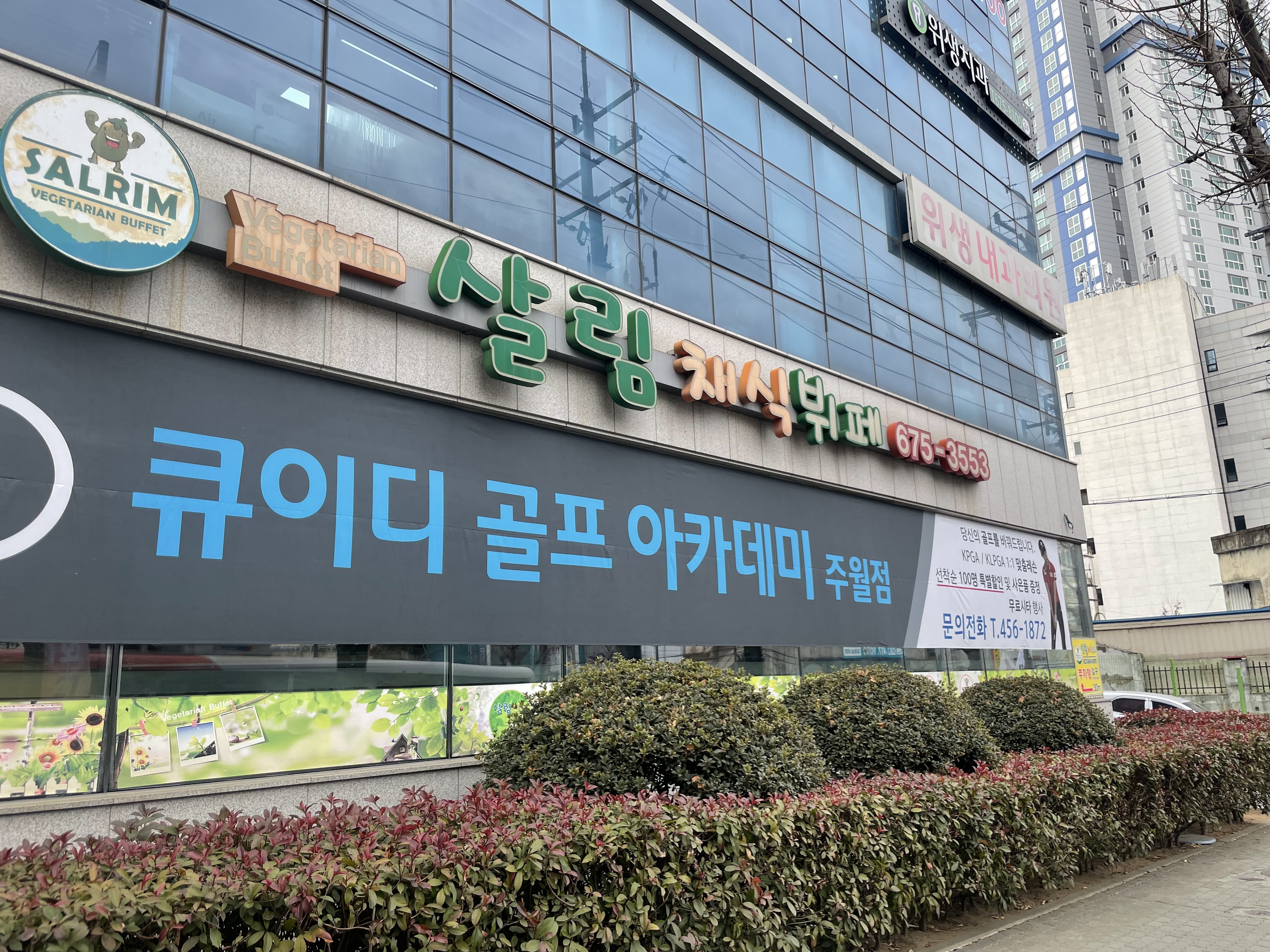 건물 외관. 큐이디 골프 아카데미 주월점 간판이 벽면에 크게 붙어 있고 위층에는 다른 업종 간판이 걸려 있습니다.