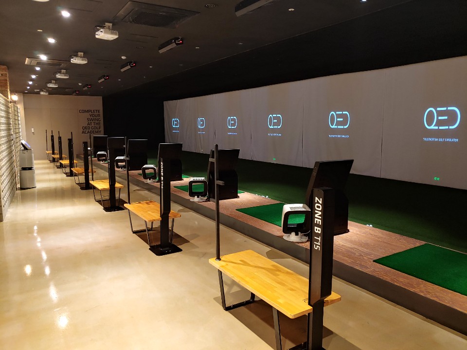 타석열. 단말 기둥에 ZONE B T15 라고 적힐 있고 뒤로 QED 로고가 스크린마다 떠 있습니다.
