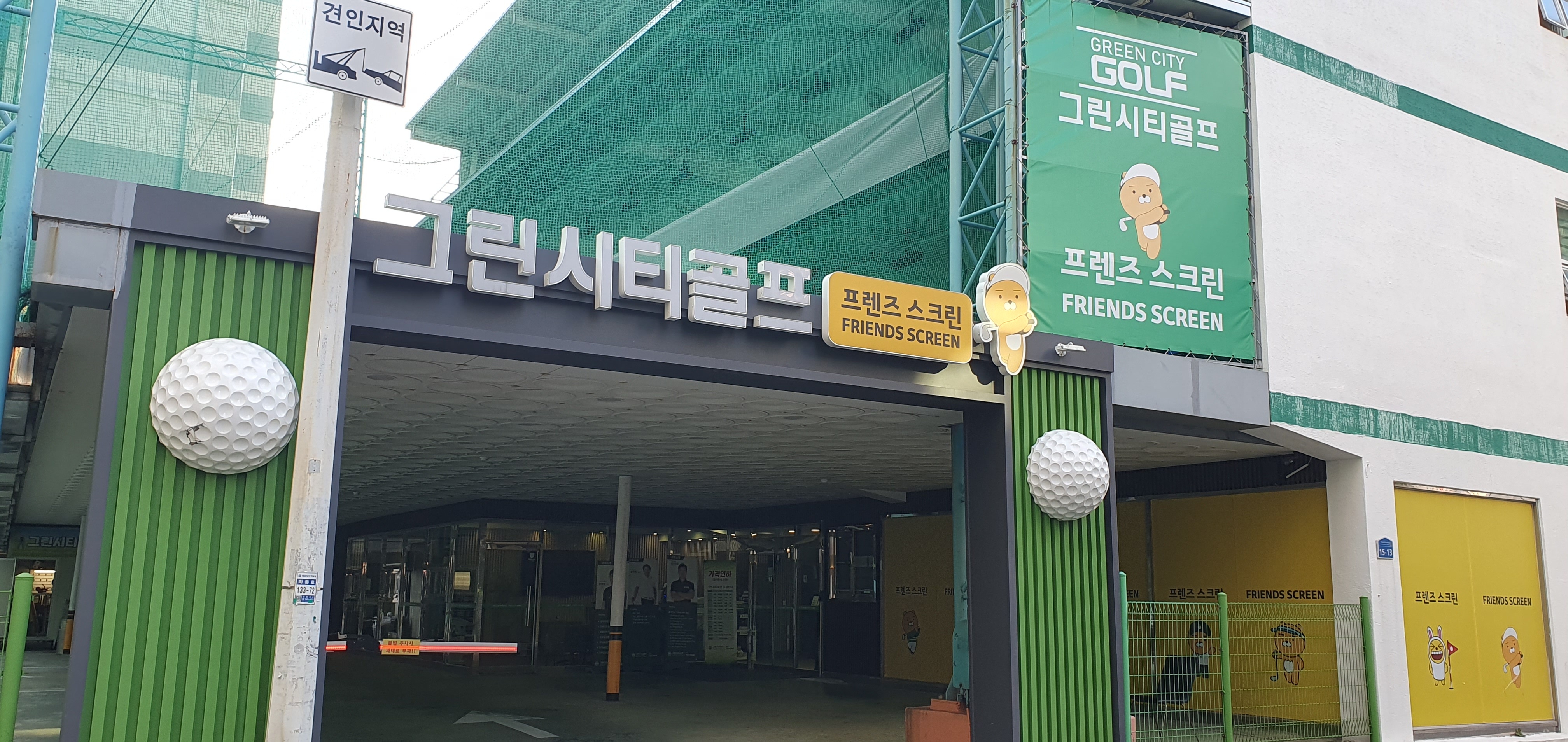매장 정면. 그린시티골프 간판 위로 실외 연습장의 초록 그물 구조물이 올라가 있습니다.